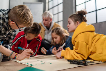 A group of happy kids with their science teacher with electric toys and robots at robotics classroom - HPIF02361