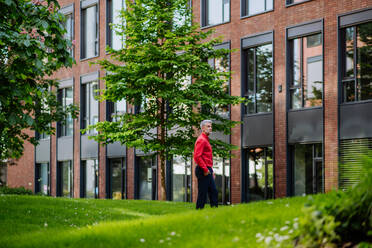 Ein Geschäftsmann zu Fuß im Park in der Nähe von Büro buliding während der Pause, Work-Life-Balance-Konzept. - HPIF02437