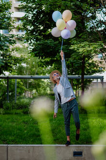 Ein lustiges Porträt von glücklichen energischen reifen Geschäftsmann hält Luftballons und zu Fuß auf Wand, Gefühl frei, Work-Life-Balance-Konzept. - HPIF02454