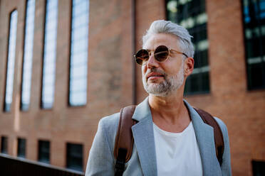 A confident man wearing backpack walking in street, businessman in casual clothes in summer on the way to work. - HPIF02469