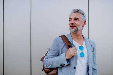 A confident man wearing backpack walking in street, businessman in casual clothes in summer on the way to work. - HPIF02503