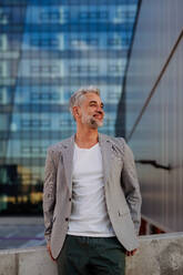 A portrait of happy energetic mature businessman in city, work life balance concept. - HPIF02522