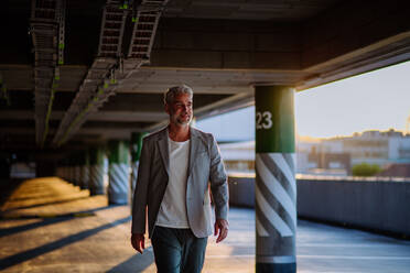 A successful happy businessman waiting in city garage, copy space, commuting concept. - HPIF02523