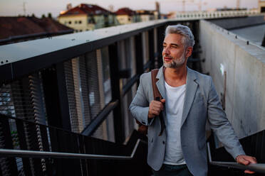 A successful happy businessman commuting in city staircase, looking away. - HPIF02534