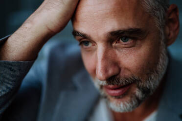 A close-up portrait of handsome businessman touching his head looking away and thinking or making some decision - HPIF02544