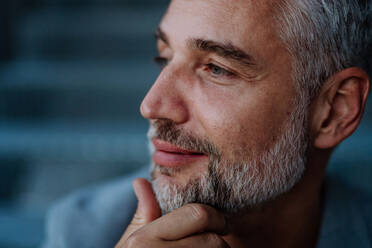 A close-up portrait of handsome businessman touching his beard, looking away and thinking or making some decision. - HPIF02545