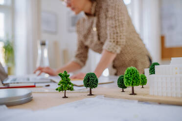 A close-up of woman architect with model of houses in office - HPIF02572