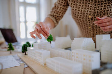 A close-up of woman architect with model of houses in office - HPIF02574