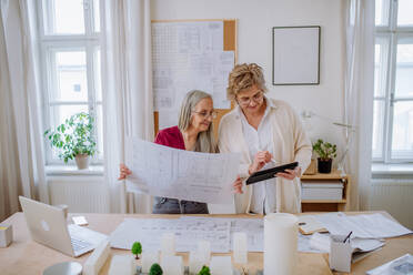 Leitende Architektinnen, die sich im Büro gemeinsam die Pläne ansehen. - HPIF02595