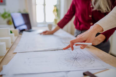 A close-up of mature women architects looking at blueprints together in office . - HPIF02598