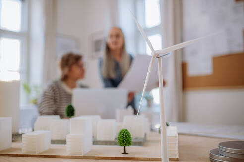 Ökoarchitektinnen bei der Arbeit im Büro, im Vordergrund eine Windkraftanlage. - HPIF02617