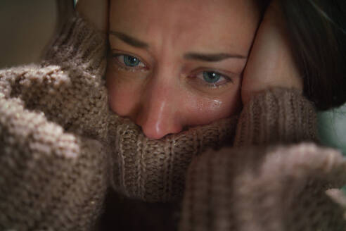 Nahaufnahme einer depressiven, einsamen Frau im mittleren Erwachsenenalter, die im Dunkeln weint. - HPIF02659