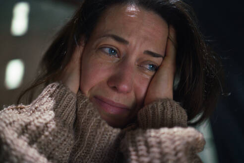 Nahaufnahme einer depressiven, einsamen Frau im mittleren Erwachsenenalter, die im Dunkeln weint. - HPIF02660