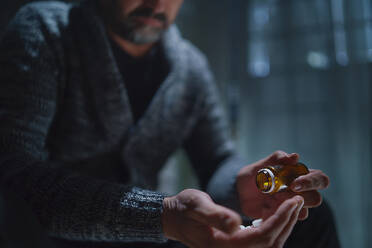 A mature man taking drug pill on dark background, mental health concept. - HPIF02666