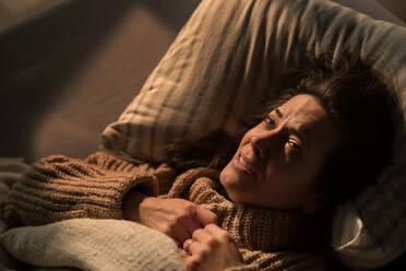 A close-up of sad woman suffering from covid depression lying in bed in night. - HPIF02687