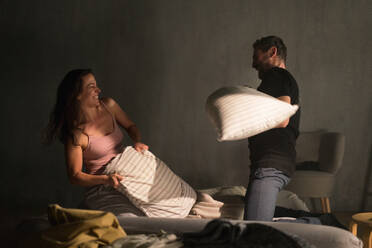 A happy couple beating with pillows on the bed in a bedroom at home. - HPIF02708