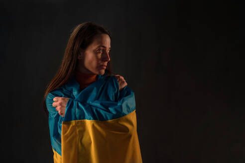 Eine traurige Frau mit ukrainischer Flagge, die sich im Krieg mit Russland auf die Seite des ukrainischen Volkes stellt. - HPIF02746