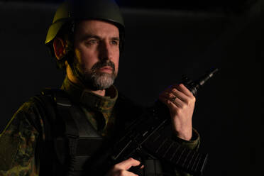 Soldat in Militäruniform und Helm mit Waffe auf schwarzem Hintergrund. - HPIF02759