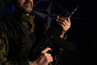 Nahaufnahme eines Soldaten in Militäruniform mit Waffe auf schwarzem Hintergrund. - HPIF02760
