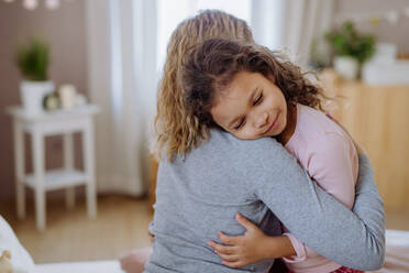 A happy mother with her little daughter hugging together on bed at home. - HPIF02876