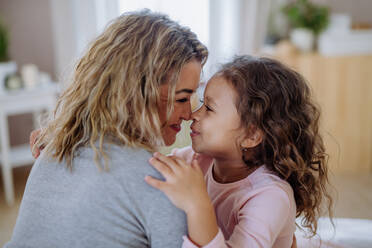 A close-up of happy mother with her little daughter hugging and looking at each other at home. - HPIF02878