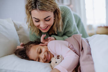 A happy mother stroking her little daughter when waking her up in morning. - HPIF02899