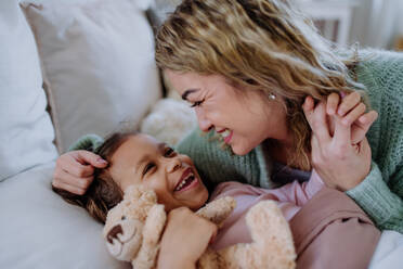 A happy mother stroking her little daughter when waking her up in morning. - HPIF02901