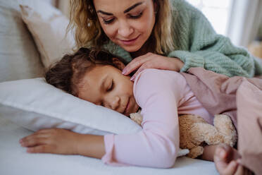 Eine glückliche Mutter, die ihre kleine Tochter streichelt, wenn sie sie am Morgen aufweckt. - HPIF02907