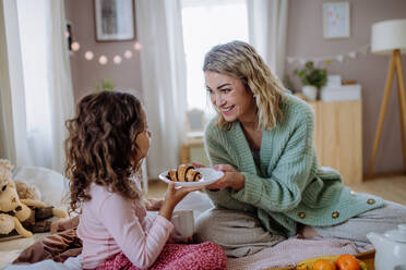 Eine glückliche Mutter mit ihrer kleinen Tochter beim gemeinsamen Frühstück im Bett. - HPIF02922