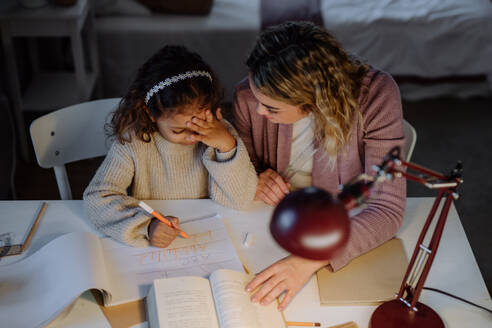 Eine hohe Winkel Ansicht des kleinen Mädchens tun Hausaufgaben mit ihrer Mutter am Abend zu Hause. - HPIF02932