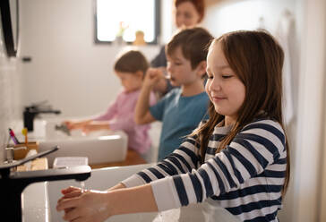 A mother with three little children in bathroom, morning routine concept. - HPIF02963