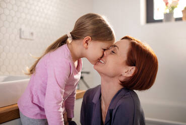 A mother kissing her little daughter in bathroom at home. - HPIF02972