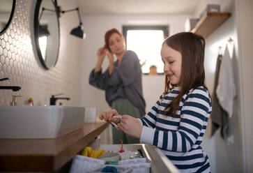 Eine Mutter mit kleiner Tochter im Badezimmer, Morgenroutine Konzept. - HPIF02990