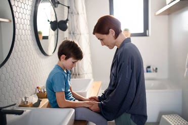 Eine Mutter tröstet ihren kleinen, aufgeregten Sohn im Badezimmer zu Hause. - HPIF03007