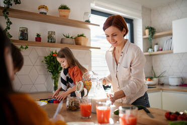 Eine Mutter von drei kleinen Kindern bereitet das Frühstück in der Küche zu Hause vor. - HPIF03011