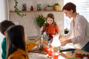 Eine Mutter von drei kleinen Kindern bereitet das Frühstück in der Küche zu Hause vor. - HPIF03012