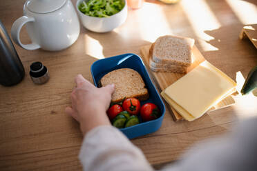 Nahaufnahme einer Mutter, die in der Küche zu Hause einen Snack für die Brotdose vorbereitet. - HPIF03014