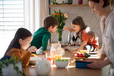 Eine Mutter von drei kleinen Kindern bereitet das Frühstück in der Küche zu Hause vor. - HPIF03021
