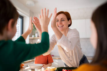A happy mother high fiving with little son when having breakfast in kitchen at home. - HPIF03030