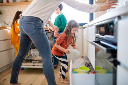 Drei kleine Kinder helfen einer Mutter in der Küche zu Hause beim Abwaschen. - HPIF03031