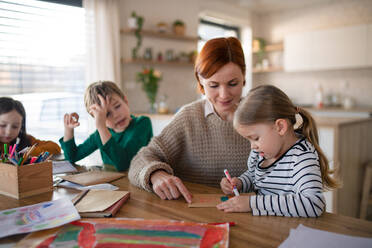 Eine Mutter von drei kleinen Kindern, die sie bei den Hausaufgaben zu Hause beaufsichtigt. - HPIF03040