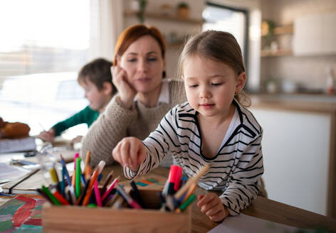 Eine Mutter von drei kleinen Kindern, die sie bei den Hausaufgaben zu Hause beaufsichtigt. - HPIF03041