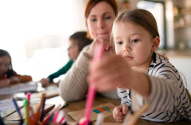 Eine Mutter von drei kleinen Kindern, die sie bei den Hausaufgaben zu Hause beaufsichtigt. - HPIF03042