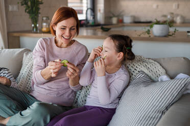 Kleine Kinder mit Mutter, die zu Hause eine Gurke auf das Gesicht legen. - HPIF03055