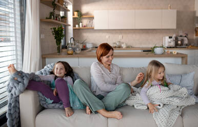A mother with two little daugter sitting on sofa and resting at home. - HPIF03067
