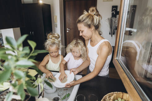 Woman with daughters washing dishes in the kitchen - SIF00578