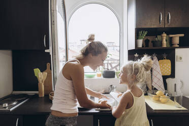 Frau und Tochter haben Spaß beim Geschirrspülen in der Küche - SIF00582