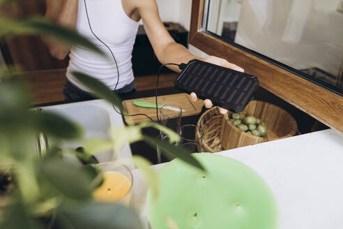 Woman holding a solar battery for charging a mobile phone in her hand - SIF00586