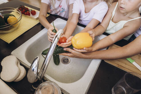 Mother and daughters washing vegetables in the kitchen - SIF00588