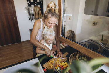 Mother and daughter preparing a salad in the kitchen together - SIF00594